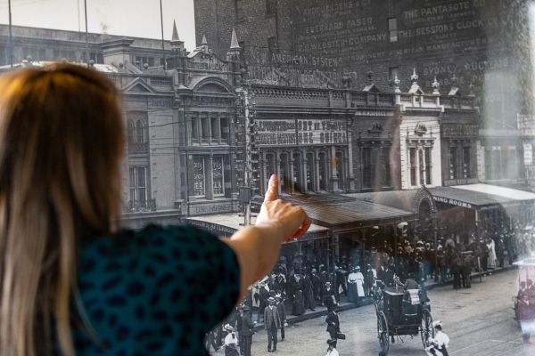 Associate Professor Rita Hardiman points out to a sign on the building saying ‘SURGEON DENTIST’ in an old photo of Swanston Street in the early 1900s, hanging inside the Young & Jackson pub in the Melbourne CBD