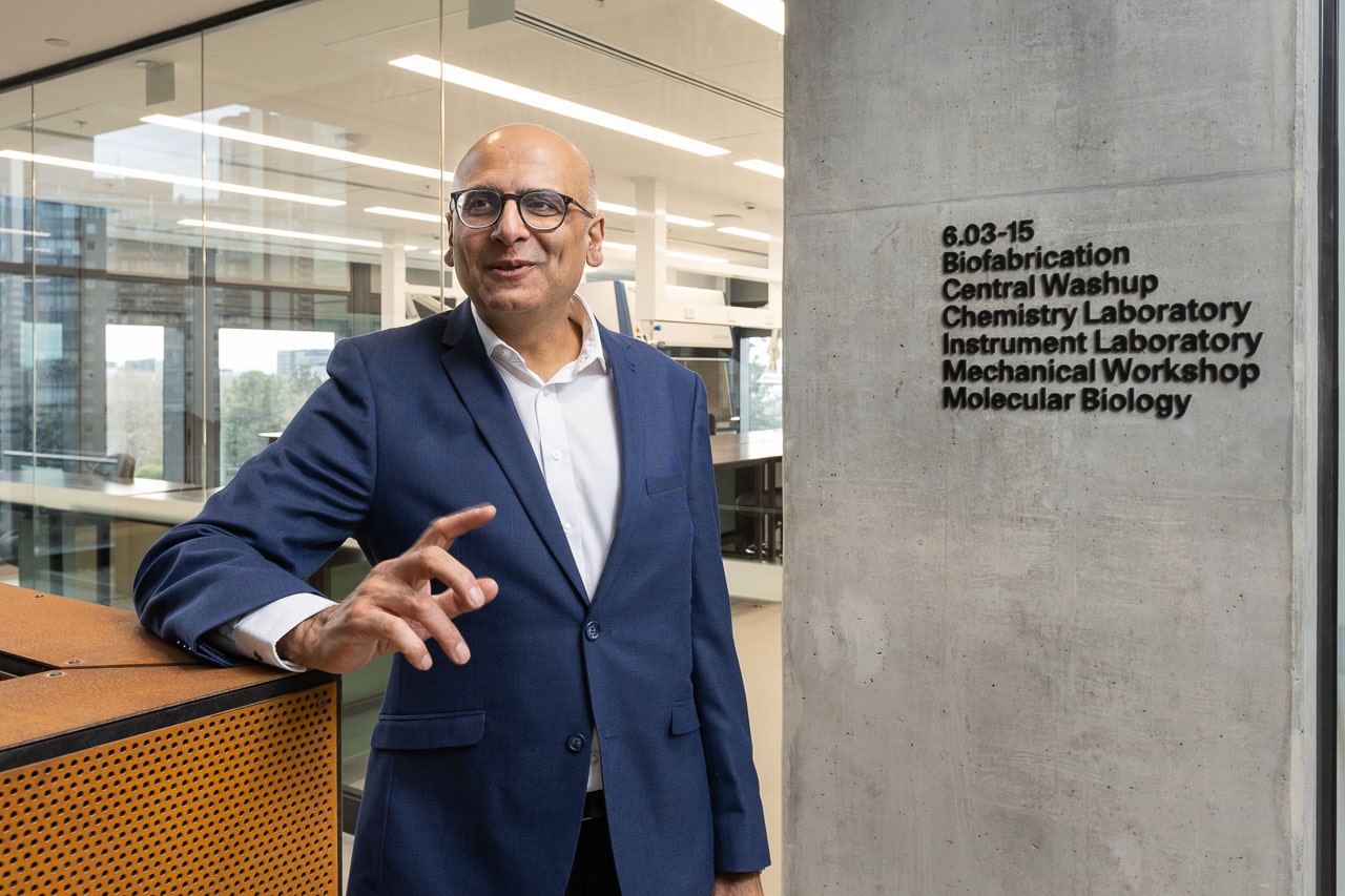 Associate Professor Roy Judge stands in front of laboratory spaces of The Aikenhead Centre for Medical Discovery, candidly explaining his research