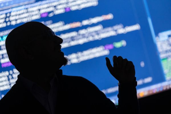 The silhouette of PhD student, Dr Rishi Ramani with a digital display showing code in the background.]