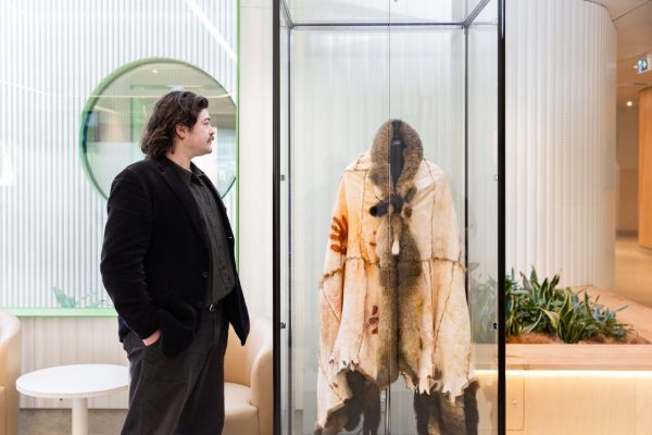 Patrick Mercer, (alum), Wadawurrung man from Ballarat and Geelong and First Nations lecturer at the Melbourne Dental School, looking at a display cabinet containing an Aboriginal possum skin cloak at The Royal Dental Hospital of Melbourne