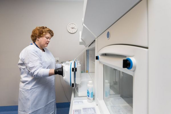 Associate Professor Butler standing at an anaerobic chamber, where P. gingivalis and other anaerobic oral bacteria are grown without oxygen