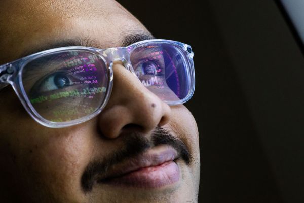 Close-up of Dr Rishi Ramani’s face, with code from a computer display reflected in his glasses